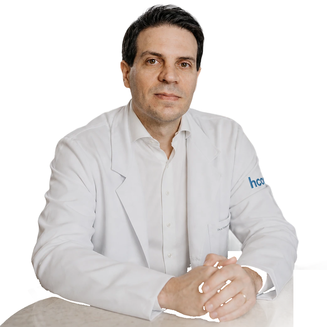 Dr. Ivan Martins, angiologista e cirurgião vascular em São Paulo, de jaleco branco, sentado à mesa do consultório